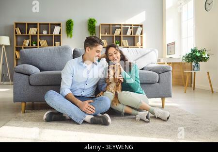Couple souriant assis avec cocker spaniel chien dans le salon lumineux confortable à la maison Banque D'Images