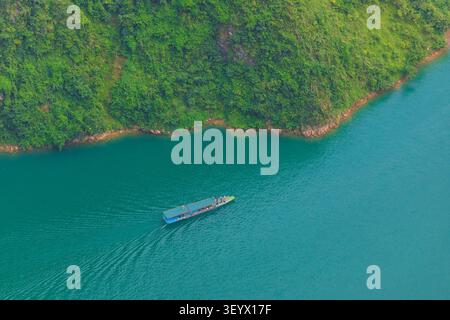 Vue aérienne d'un petit bateau naviguant sur les eaux turquoises de la rivière Nho que, entouré de montagnes verdoyantes à Meo Vac, Tuyen Quang, Vietnam Banque D'Images