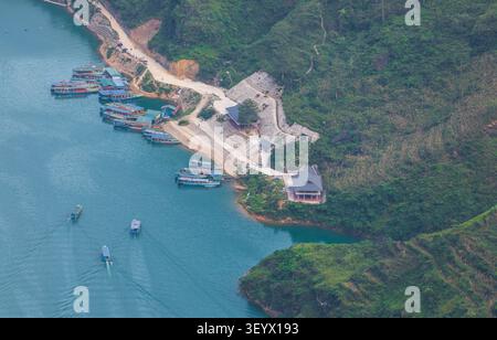 Vue aérienne de la rivière Nho que avec des bateaux touristiques amarrés le long de la jetée en béton et se déplaçant à travers l'eau turquoise, entouré de montages verdoyants Banque D'Images