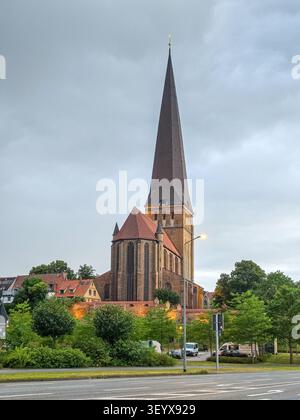 Église historique en briques dans la ville de Rostock avec un haut clocher gothique dans une ville européenne sous un ciel dramatique du soir Banque D'Images