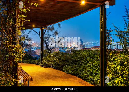 Pergola illuminée dans le parc Chambarakand encadrant une vue panoramique nocturne sur Bakou horizon avec Port Baku Tower et Crescent Hotel. Bakou, Azerbaïdjan. Banque D'Images