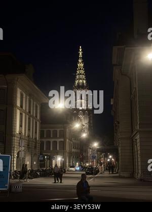 Scène de rue nocturne avec vue sur la flèche gothique illuminée de la cathédrale de Berne, Berne, Suisse Banque D'Images