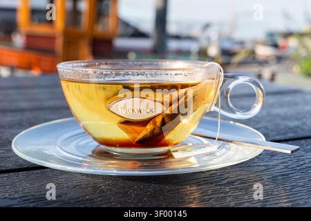 Tasse de thé noir Pickwick servi dans une tasse en verre transparent sur une soucoupe transparente Banque D'Images