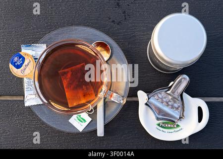 Tasse de thé noir Pickwick servi dans une tasse en verre transparent sur une soucoupe transparente Banque D'Images