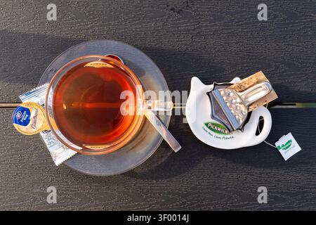 Tasse de thé noir Pickwick servi dans une tasse en verre transparent sur une soucoupe transparente Banque D'Images