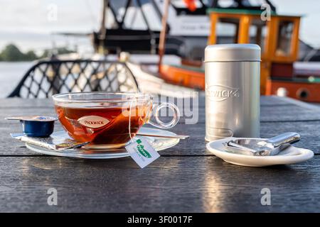 Tasse de thé noir Pickwick servi dans une tasse en verre transparent sur une soucoupe transparente Banque D'Images