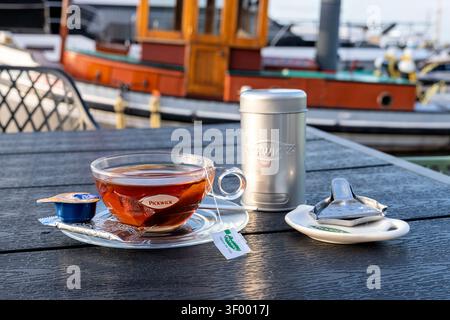 Tasse de thé noir Pickwick servi dans une tasse en verre transparent sur une soucoupe transparente Banque D'Images