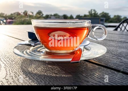 Tasse de thé noir Pickwick servi dans une tasse en verre transparent sur une soucoupe transparente Banque D'Images