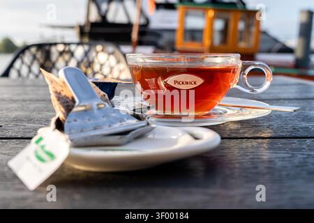 Tasse de thé noir Pickwick servi dans une tasse en verre transparent sur une soucoupe transparente Banque D'Images