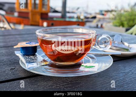 Tasse de thé noir Pickwick servi dans une tasse en verre transparent sur une soucoupe transparente Banque D'Images