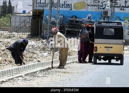QUETTA, PAKISTAN - 05 juillet 2026 : les travailleurs engagés dans la construction de routes sur la route Samangali à Quetta le dimanche 5 juillet 2026 contribuent au développement des infrastructures de la région. La scène, mettant en vedette des ouvriers le long d'une bordure de béton nouvellement construite, souligne les efforts en cours pour améliorer les réseaux de transport locaux. La présence d'un auto-rickshaw de marque Sazgar met en évidence la vie urbaine quotidienne au milieu de ce développement. Ces projets sont essentiels pour améliorer la connectivité et la croissance économique à Quetta, soulignant l'importance de la modernisation des infrastructures dans les zones urbaines. (Sami Banque D'Images