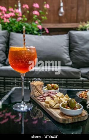 Cocktail Aperol Spritz orange vif servi dans un grand verre à pied avec une paille rayée, garni d'une tranche d'orange fraîche Banque D'Images