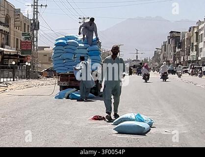 QUETTA, PAKISTAN - 05-Jul-2026 : une scène de rue animée sur Samangali Road à Quetta s'est transformée en événements lorsqu'un sac de farine est tombé d'un camion surchargé le dimanche 5 juillet 2026. L'incident a été observé au milieu d'une activité animée, avec trois hommes gérant la cargaison de sacs bleu clair. Cet événement souligne les défis permanents en matière de sécurité routière associés aux véhicules surchargés dans les zones urbaines, soulignant la nécessité de renforcer les mesures réglementaires. La toile de fond des rues poussiéreuses et animées et de la circulation achalandée accentue l'urgence d'une intervention gouvernementale pour prévenir les dangers potentiels. (Sami Khan/PP Banque D'Images