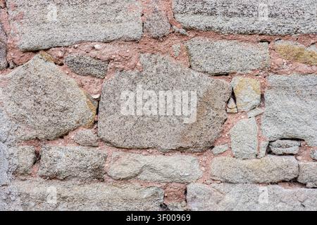Le mur en pierre altérée remplit le cadre d'une texture naturelle rugueuse. Fond rustique avec des tons neutres et un espace de copie, utile pour la conception, la construction, Banque D'Images