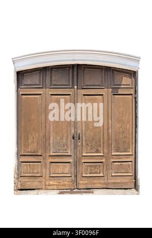 Vieille porte de garage en bois vieilli avec quatre sections lambrissées sous une arche en pierre blanche, montrant le vieillissement naturel, le vernis pelable et les textures rustiques o Banque D'Images