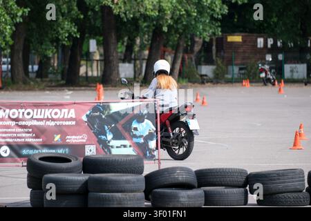 KIEV, UKRAINE, 5 JUILLET 2026, étudiant conduisant une moto pendant une leçon pratique sur un terrain d'entraînement de moto avec des cônes de circulation et des obstacles de sécurité Banque D'Images