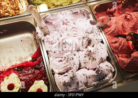 Assortiment de saveurs de glace et de sorbet aux fruits dans des contenants d'exposition. Fond de dessert glacé pour une rafraîchissement estival en douceurs et des friandises colorées. Banque D'Images