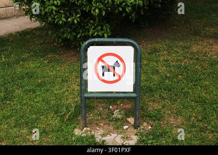 Panneau "Chiens interdits" installé sur une pelouse verte dans un espace extérieur public. Contexte réglementaire pour les restrictions relatives aux animaux de compagnie règles du parc propreté sécurité Banque D'Images