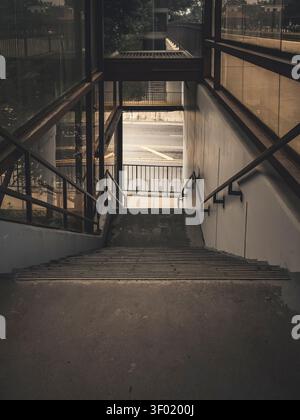 Vue symétrique en descendant des escaliers piétonniers en béton menant à un passage souterrain à une plate-forme de gare ferroviaire de transit moderne Banque D'Images