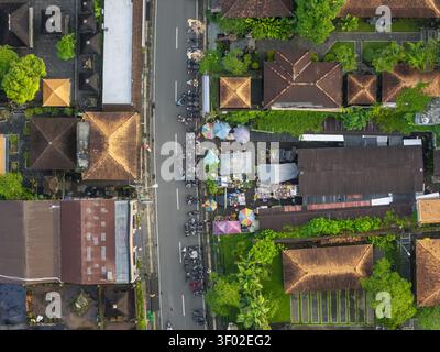 Vue aérienne du marché de rue animé d'Ubud avec l'architecture traditionnelle balinaise, des parasols colorés et des motos garées à Ubud, Bali, in Banque D'Images