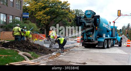 Ouvriers de la construction portant des gilets de sécurité jaunes posant un trottoir de ciment à un immeuble d'habitation. St Paul Minnesota MN États-Unis Banque D'Images