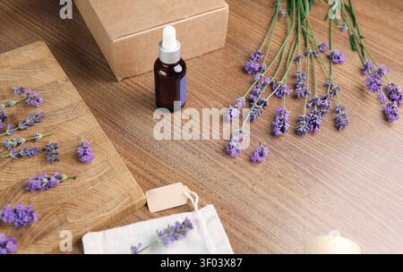 Bouteille d'huile de lavande et sachet avec fleurs sur planche de bois. Composition à plat pour créateur de contenu de médias sociaux et toile de fond de blogs Banque D'Images