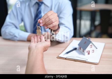 Agent immobilier remettant les clés de la maison au nouveau propriétaire durin Banque D'Images