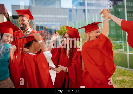 Groupe d'étudiants universitaires joyeux célébrant en plein air, regardant la caméra, concept de remise des diplômes. Banque D'Images
