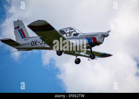 Avion léger en vol contre un ciel bleu nuageux Banque D'Images