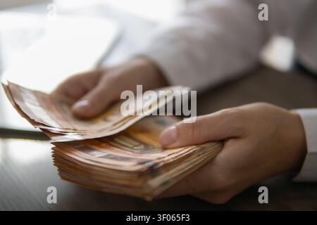 Personne comptant une pile de billets de 50 euros, gérant ses finances personnelles, budgétisant les dépenses, recevant des revenus ou effectuant des paiements en espèces Banque D'Images