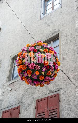 Des décorations florales sphériques colorées sont suspendues au-dessus d'une zone piétonne en Allemagne. La zone compte de vieux bâtiments et est animée de gens qui profitent th Banque D'Images