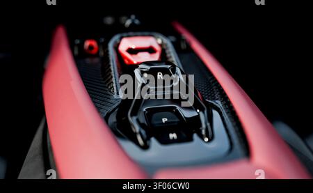 Gros plan d'une console centrale de voiture sport haute performance dotée d'un sélecteur de vitesse brillant avec marquages R et P, d'une garniture en fibre de carbone et d'un accent rouge vif Banque D'Images