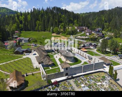 Complexe de monastère fortifié dans la zone rurale et boisée, entouré de collines verdoyantes et d'un village, vue aérienne, monastère Saint George, monastère Voronet, Vo Banque D'Images