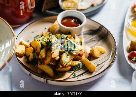 Côtelettes de pommes de terre dorées rôties garnies de persil frais et servies avec une sauce de trempage sur une assiette en céramique. Délicieuse entrée ou accompagnement fait maison dans un cadre de restaurant chaleureux. Banque D'Images