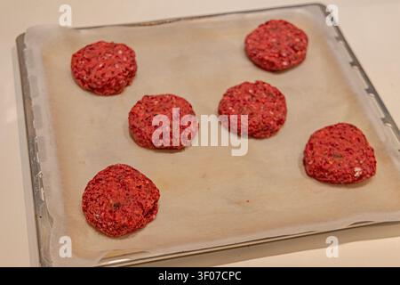 Burger végétalien aux galettes crues betterave et haricots rouges sur une plaque de cuisson Banque D'Images