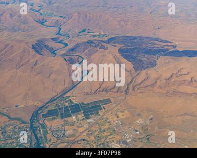 Vue aérienne à haute altitude de la rivière Yakima serpentant à travers les montagnes arides et les terres agricoles irriguées dans l'État de Washington. Banque D'Images
