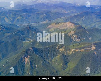 Vue aérienne à haute altitude des crêtes montagneuses verdoyantes et des vallées profondes couvertes de forêts denses dans le nord-ouest du Pacifique. Banque D'Images