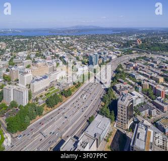 High-angle aerial view of a busy multi-lane highway cutting through Seattles urban landscape with Lake Washington and distant mountains in the backgro Banque D'Images