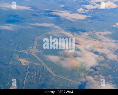 Vue en haute altitude des forêts vertes, des routes forestières droites et des nuages blancs éparpillés sur le terrain dans l'État de Washington. Banque D'Images