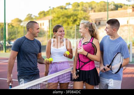 Des hommes et des femmes qui discutent sur un court de tennis extérieur Banque D'Images