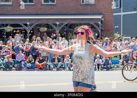 État de Washington, États-Unis, 20 juin 2026 - Une femme portant un haut en paillettes argentées, un short en denim, des lunettes de soleil roses et une couronne de fleurs se produit avec un Banque D'Images
