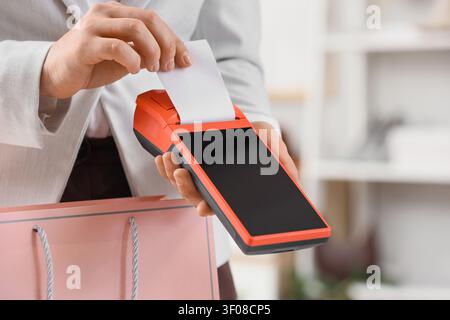 Personne tenant un terminal de paiement avec reçu et sac à provisions Banque D'Images