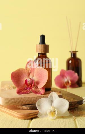 Bouteille d'huile essentielle d'aromathérapie avec fleurs d'orchidée sur planches de bois Banque D'Images
