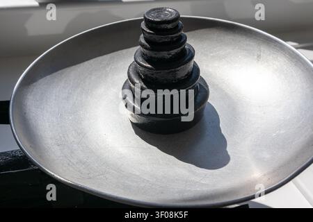 Balance de cuisine vintage en métal avec un plateau tenant une pyramide empilée de poids impériaux traditionnels en fer noir Banque D'Images