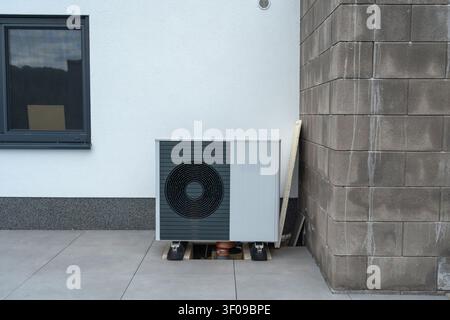 une unité de climatisation stationnaire installée du côté extérieur d'un bâtiment résidentiel, mettant en valeur un design neutre et fonctionnel avec du gris et Banque D'Images