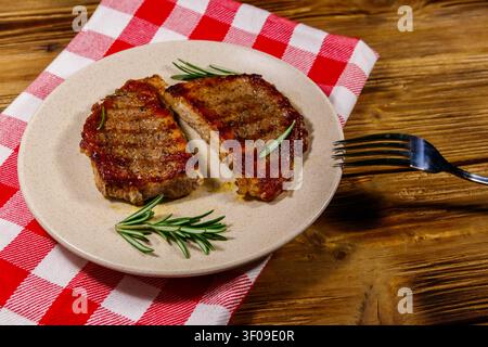 Steaks de porc grillés au romarin sur une table en bois Banque D'Images