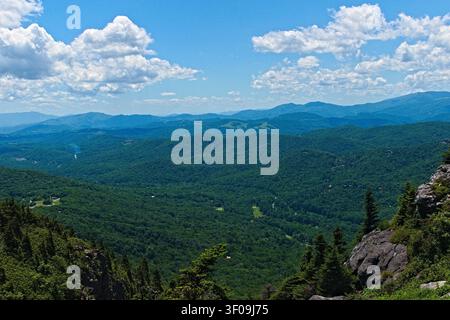 Une vue panoramique à couper le souffle sur les chaînes de collines bleues ondulantes et les vallées sous un vaste ciel bleu parsemé de nuages blancs et moelleux. Banque D'Images