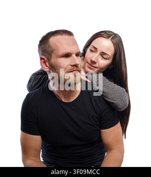 Une femme embrasse doucement un homme barbu par derrière sur un fond blanc. Banque D'Images
