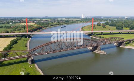 Vue aérienne du pont ferroviaire Haus-Knipp et du pont routier moderne enjambant le Rhin avec berges vertes et arrière-plan industriel à Duisbur Banque D'Images
