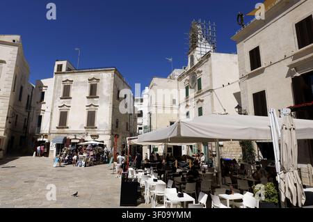 Place Piazza Vittorio Emanuele II à Polignano a Mare, Italie, avec une architecture ancienne, des cafés en plein air et des touristes profitant d'une journée ensoleillée. Italie, ap Banque D'Images